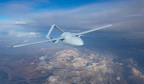 Unmanned military drone uav flying in the air, reconnaissance flight over the territory above the snow-capped mountains hills relief.